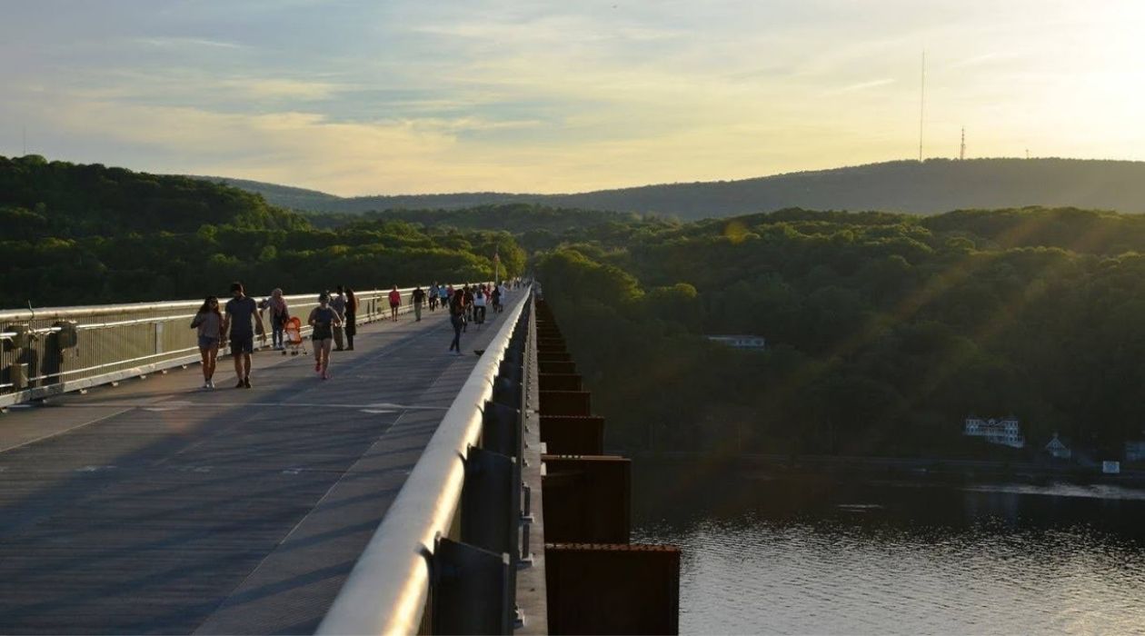 Elevated pedestrian bridge over Hudson River with green mountains in background